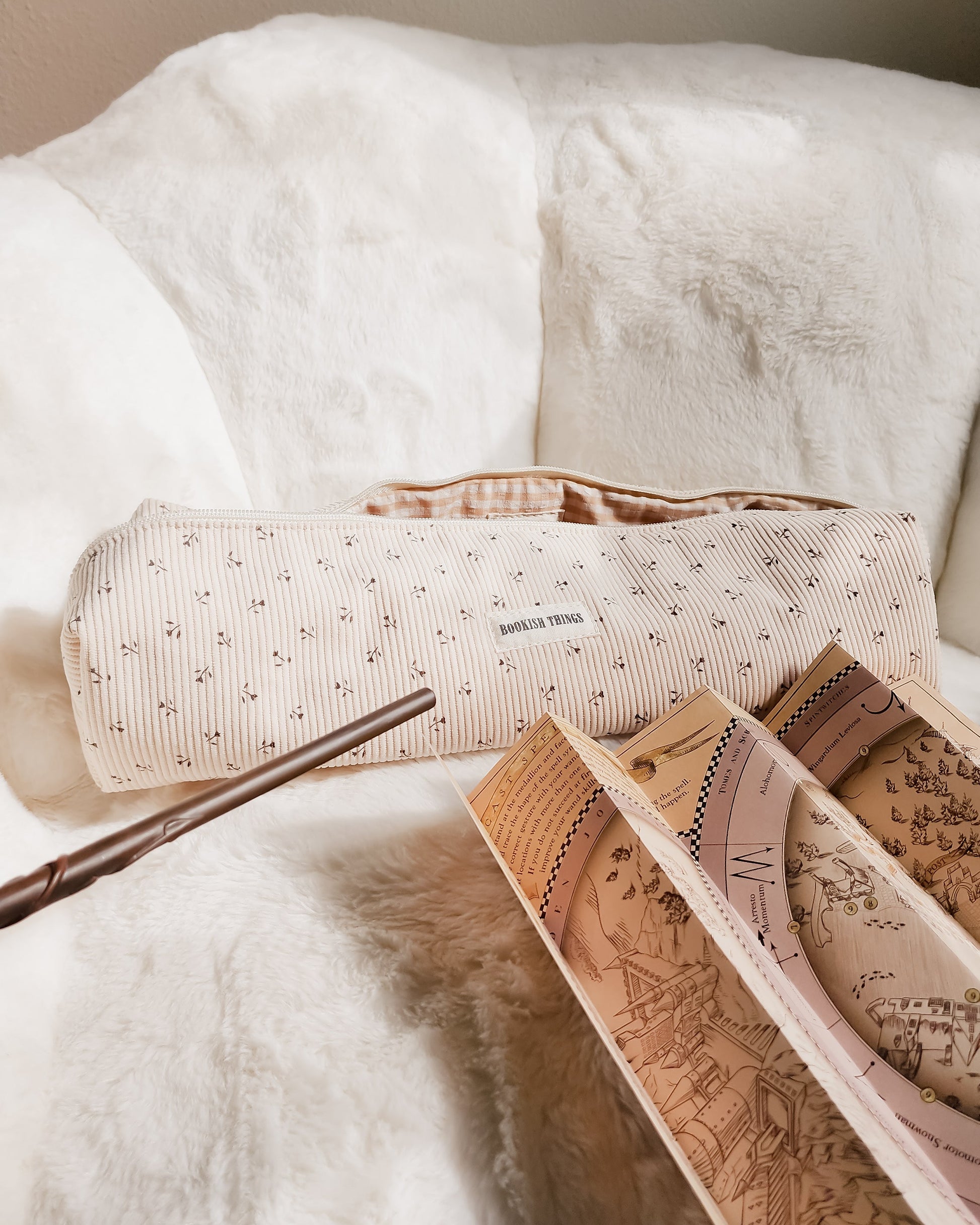 Bookish Things corduroy travel bag with map and wand on white faux fur chair