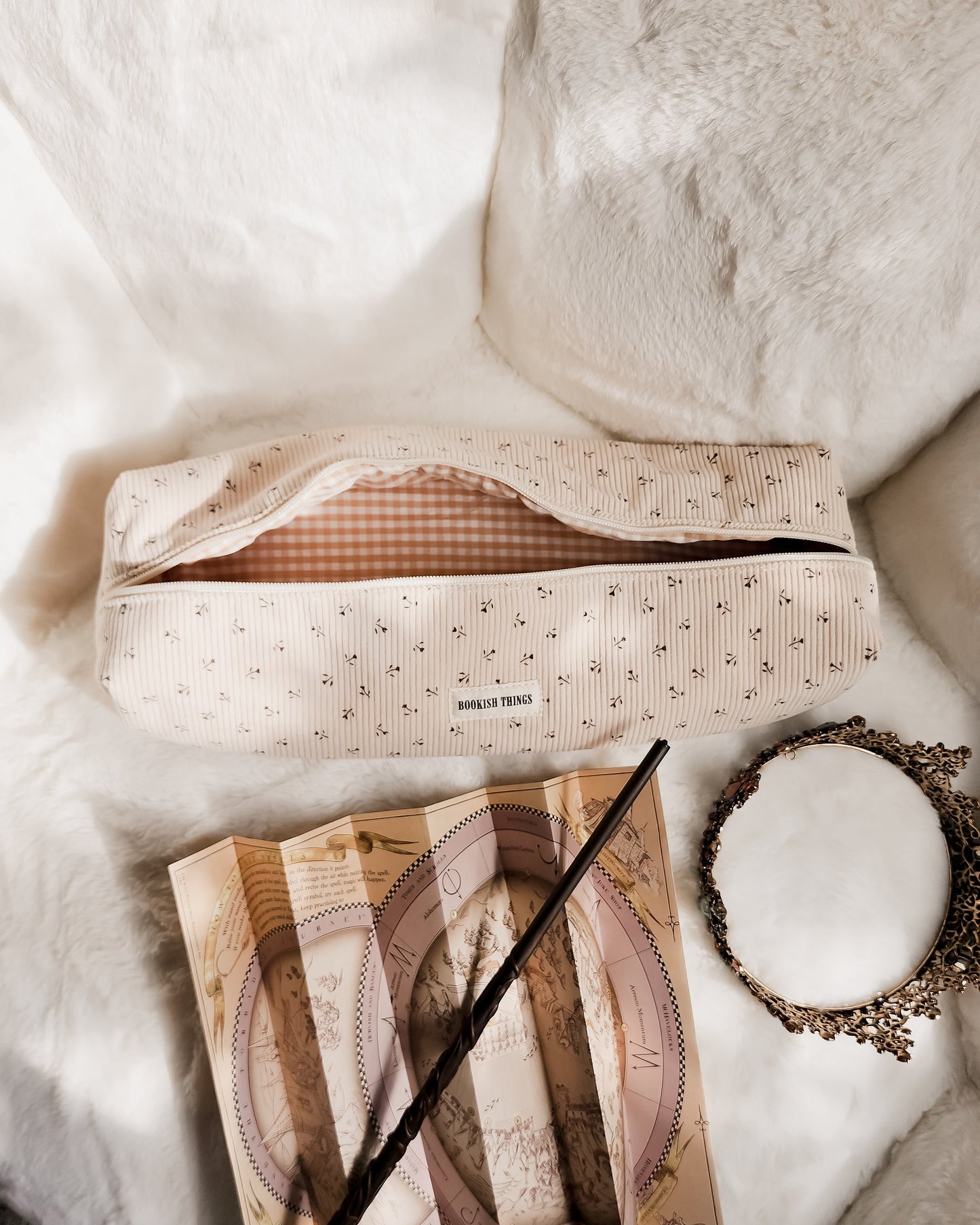 Corduroy hair tool travel bag with floral print, vintage map, wand, and ornate mirror on white fur
