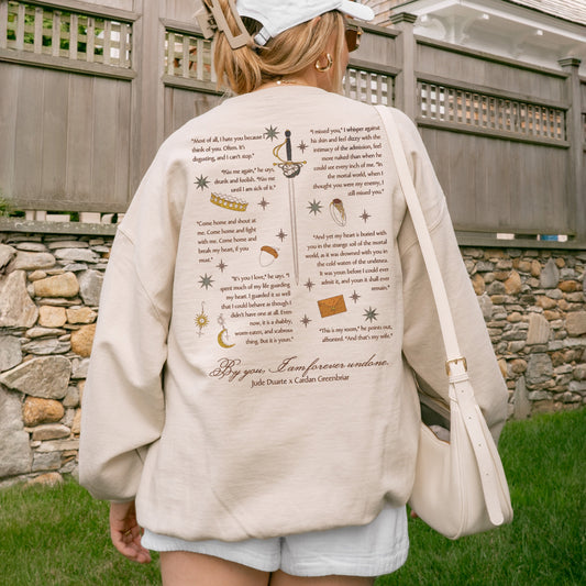 Woman wearing a cream sweatshirt with book quotes and illustrations on the back, outdoors
