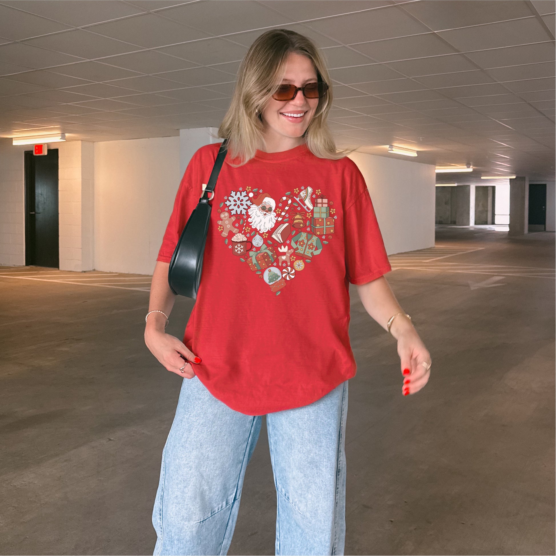 Woman wearing red Christmas t-shirt with festive heart design, jeans, and sunglasses