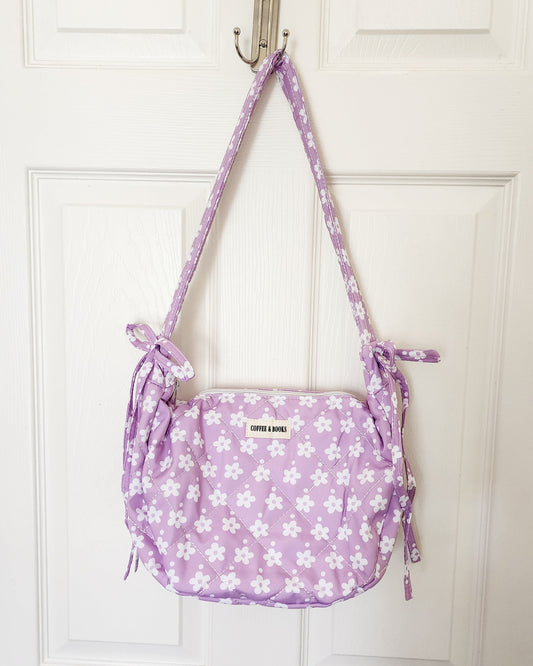 Purple floral-patterned bag hanging on a white door handle.