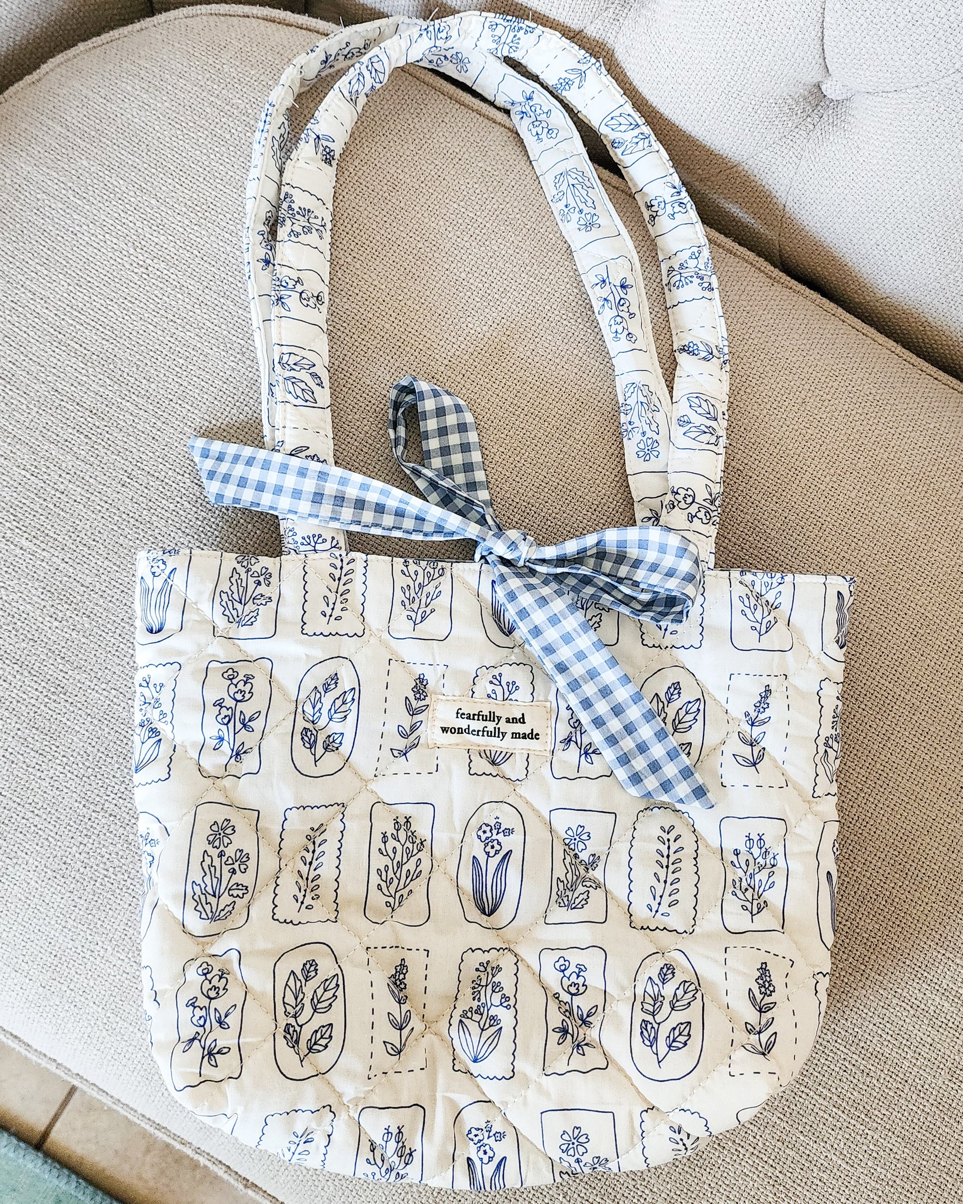 Cotton quilted tote bag with blue floral pattern and gingham bow, text patch reads 'fearfully and wonderfully made'.