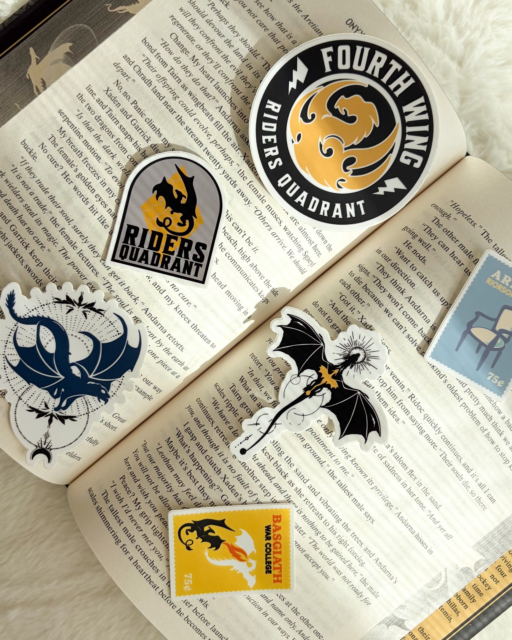 Open book with various stickers featuring dragons and text on a textured surface.