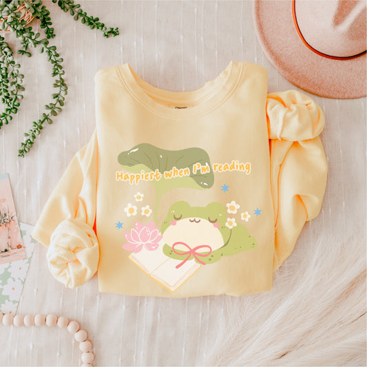 Cute yellow sweatshirt with frog, book, lotus flower, and 'Happiest when I'm reading' text