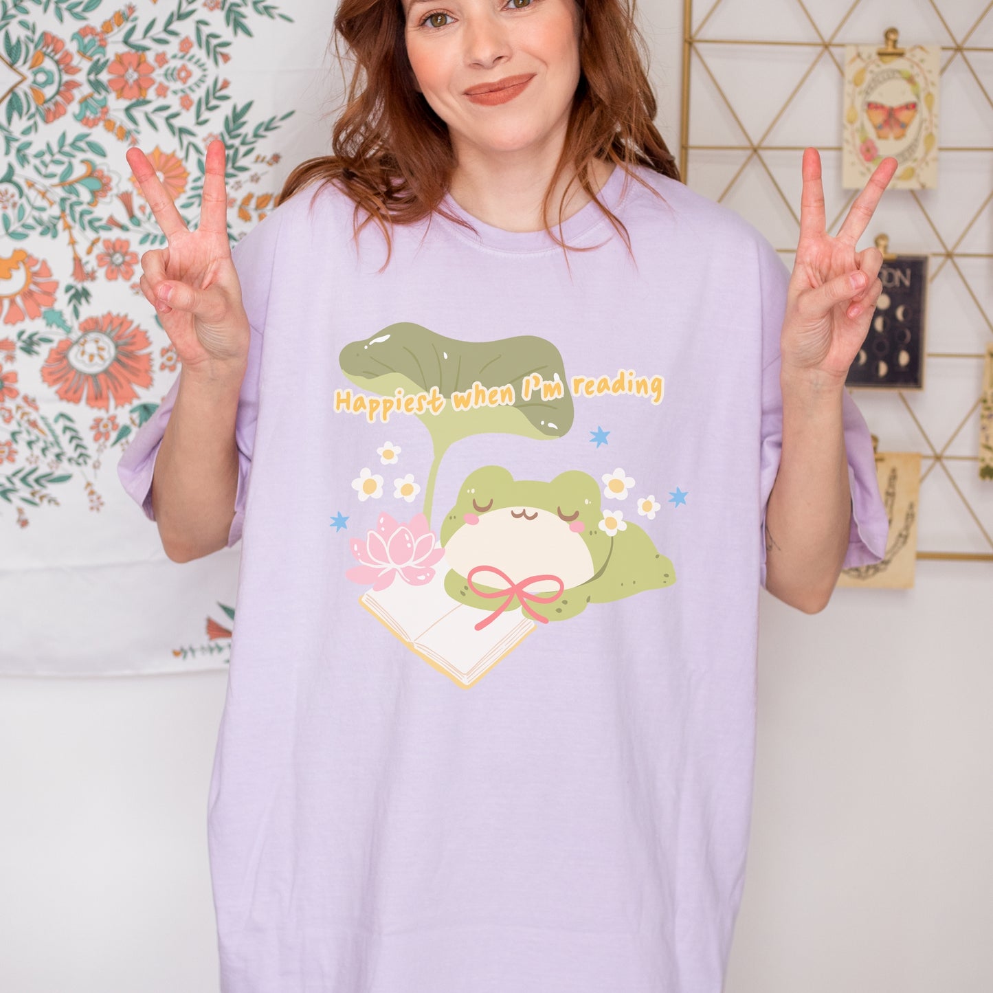 Woman wearing lavender t-shirt with cute frog, book, and 'Happiest when I'm reading' text.