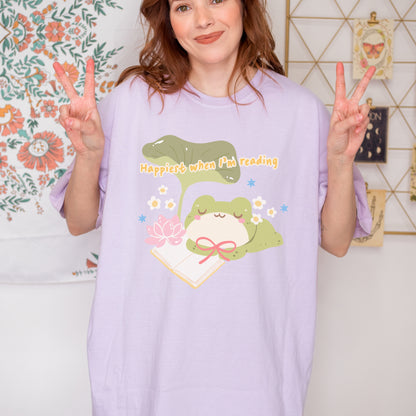 Woman wearing lavender t-shirt with cute frog, book, and 'Happiest when I'm reading' text.