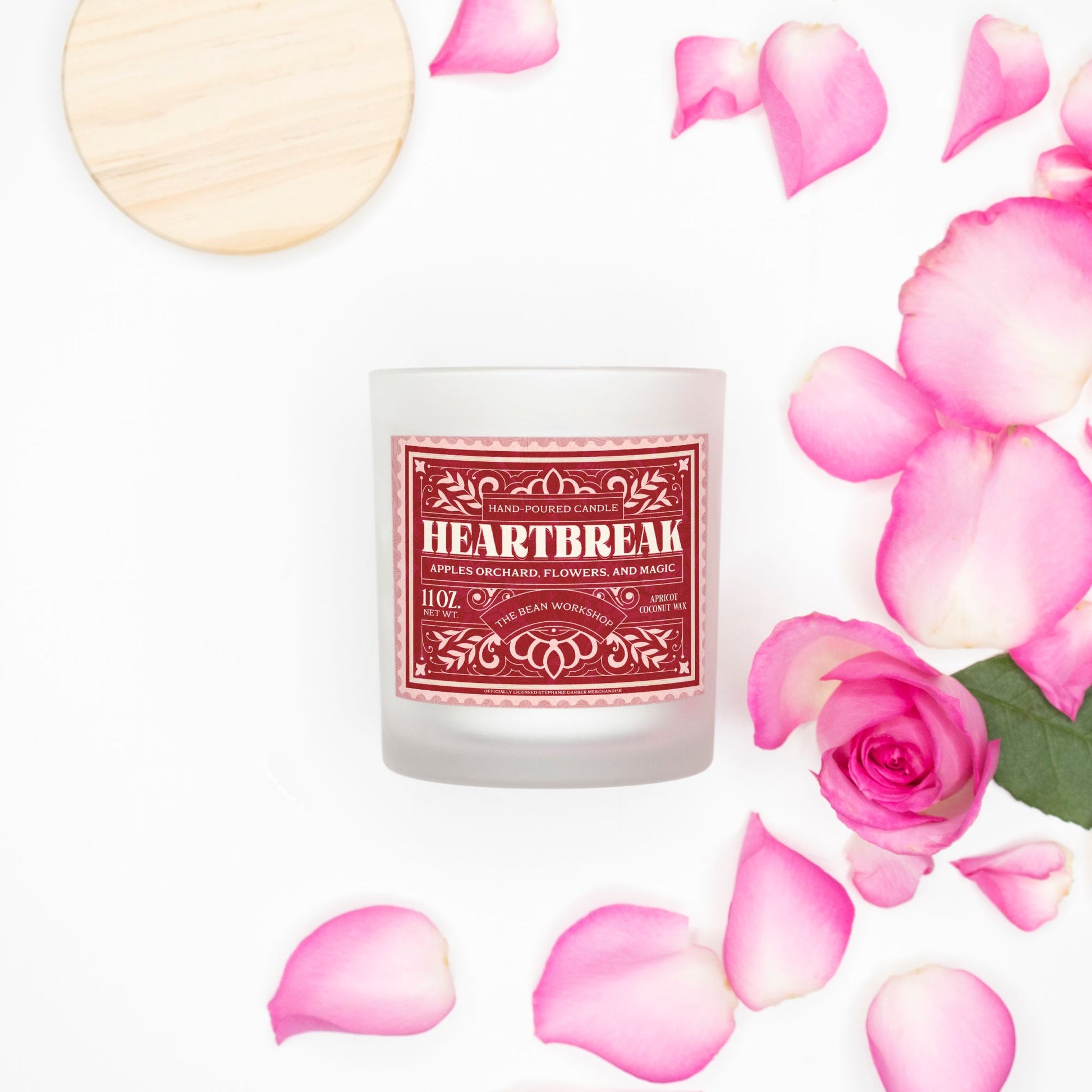Heartbreak candle in frosted glass with pink wood wick, surrounded by pink rose petals.