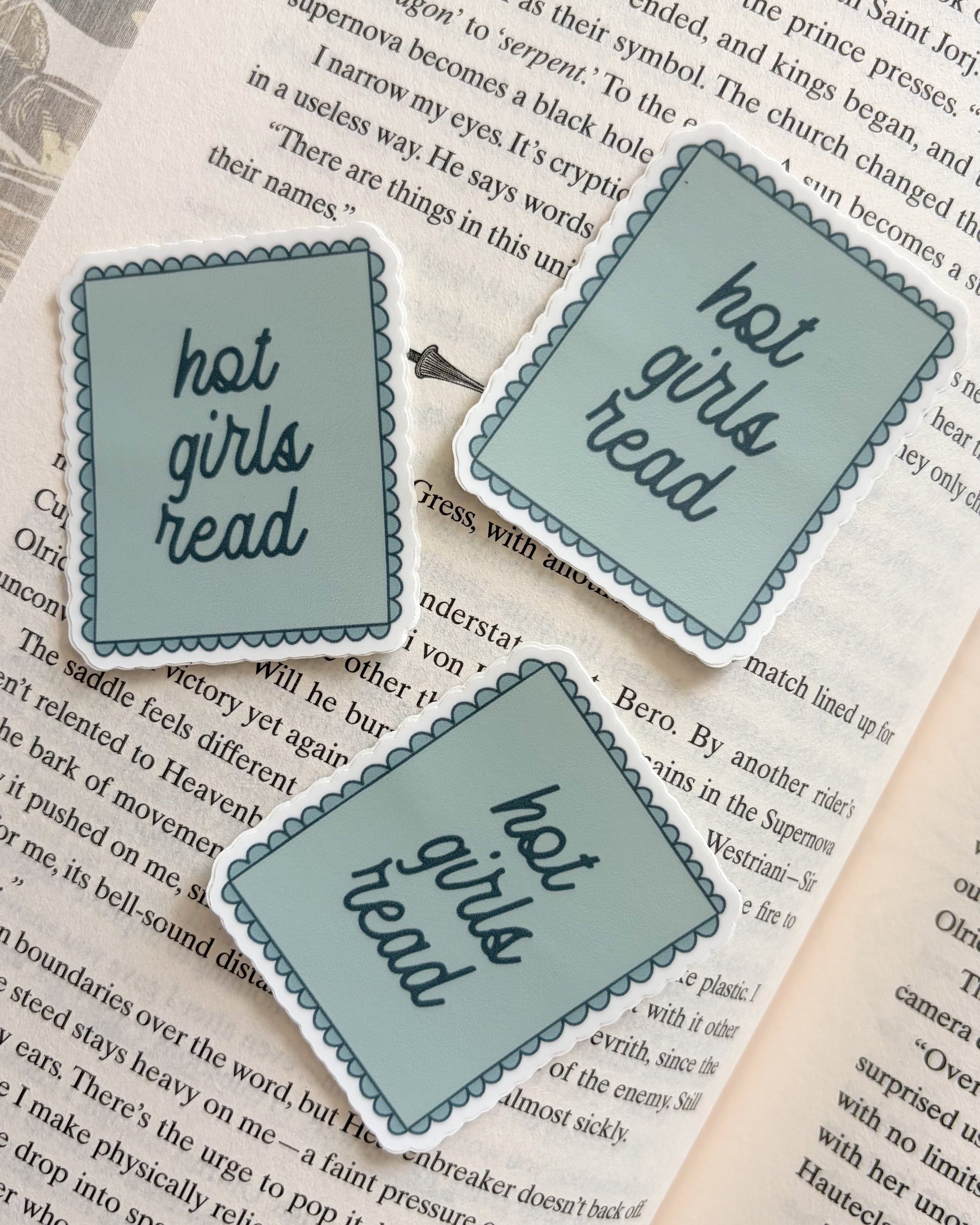 Three 'hot girls read' stickers on an open book page, bookish reading merch for readers.