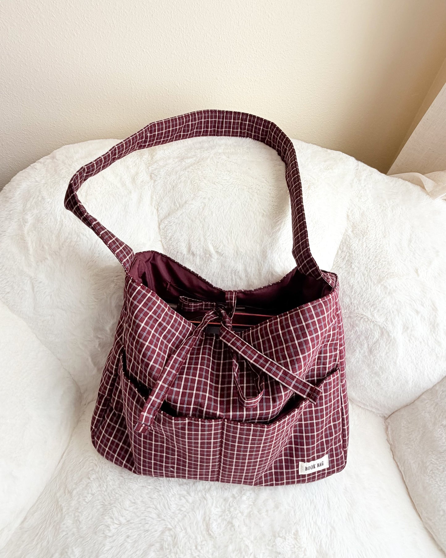 Plaid patterned bag with a bow on a white surface