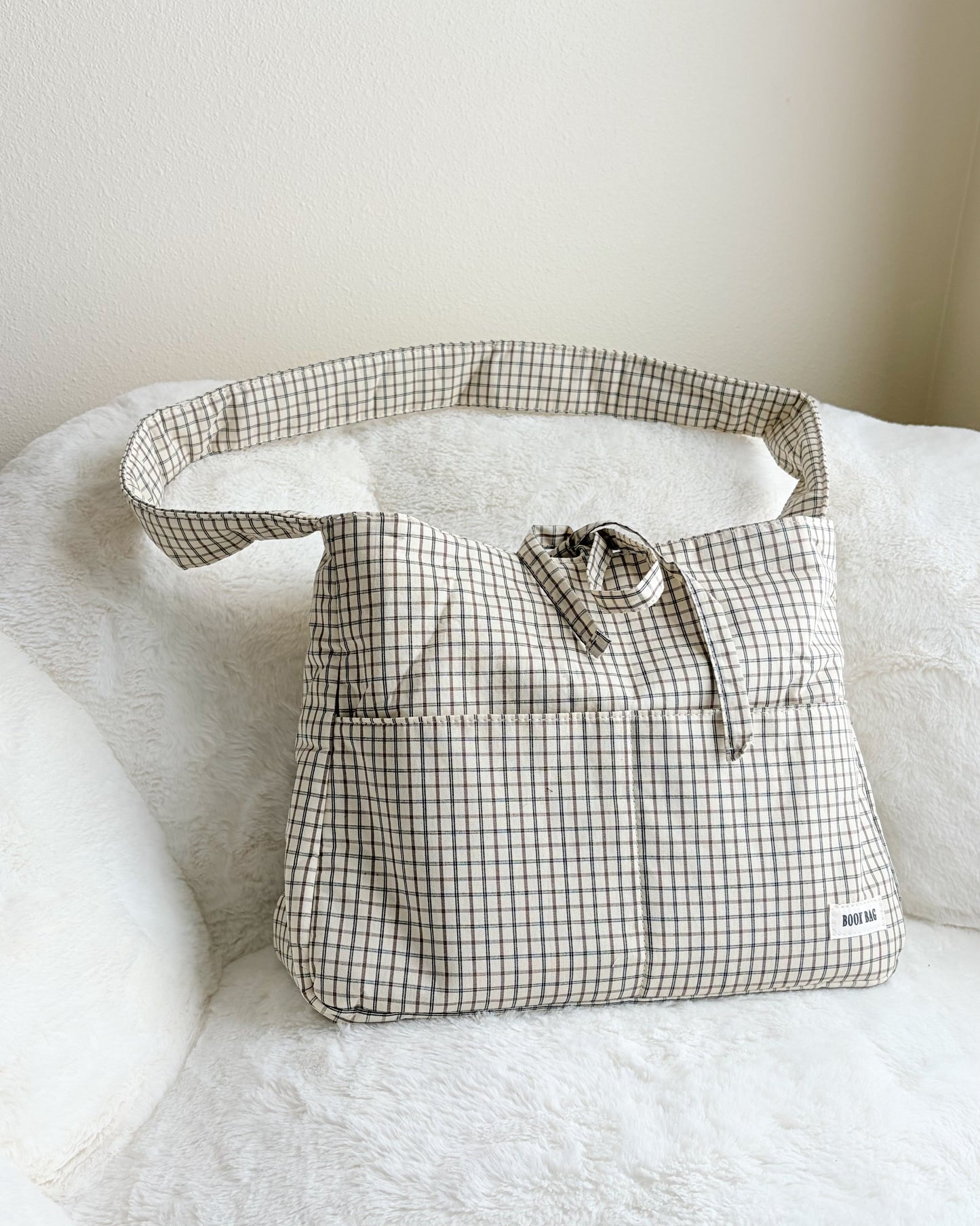 Plaid-patterned bag on a white surface with a neutral background