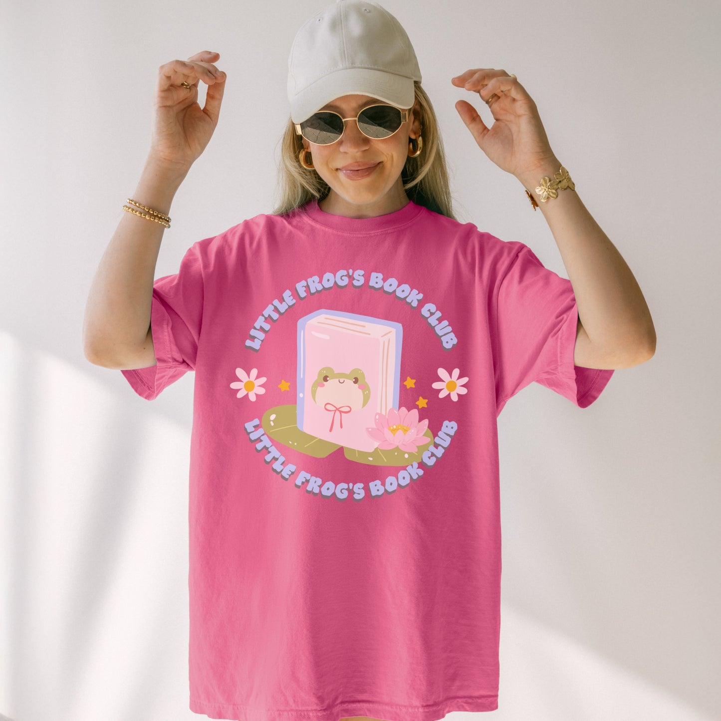 Woman wearing pink Little Frog's Book Club T-shirt with cute frog, book, and lotus graphic