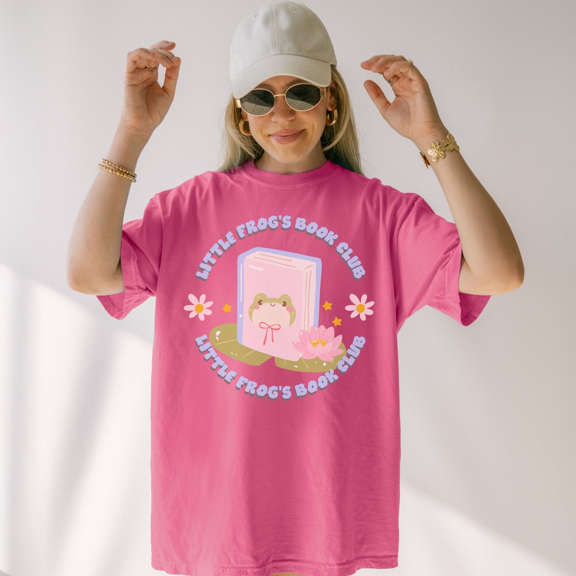 Woman wearing pink Little Frog's Book Club T-shirt with cute frog, book, and lotus graphic