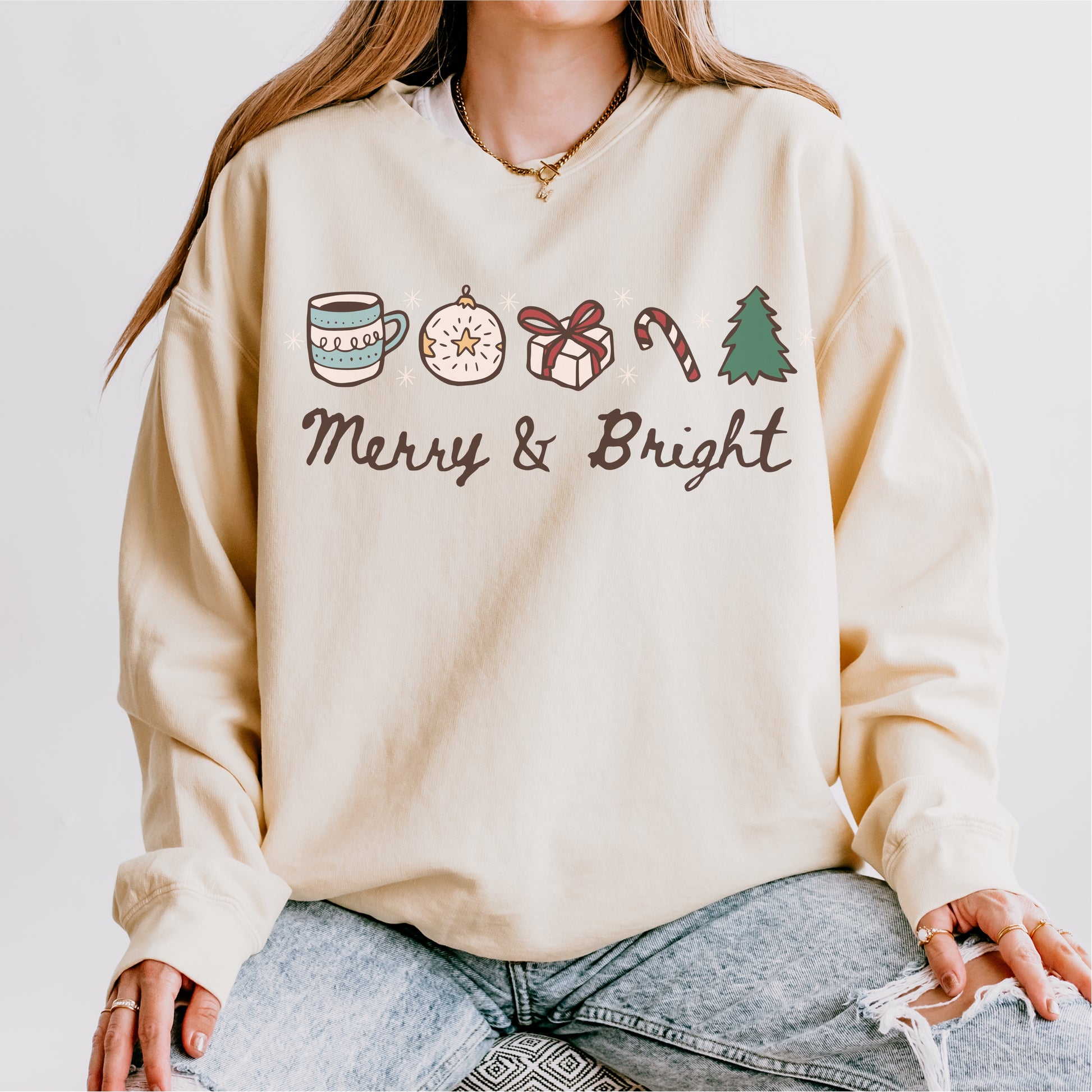 Cream fleece sweatshirt with holiday icons and 'Merry & Bright' text, cozy winter apparel.