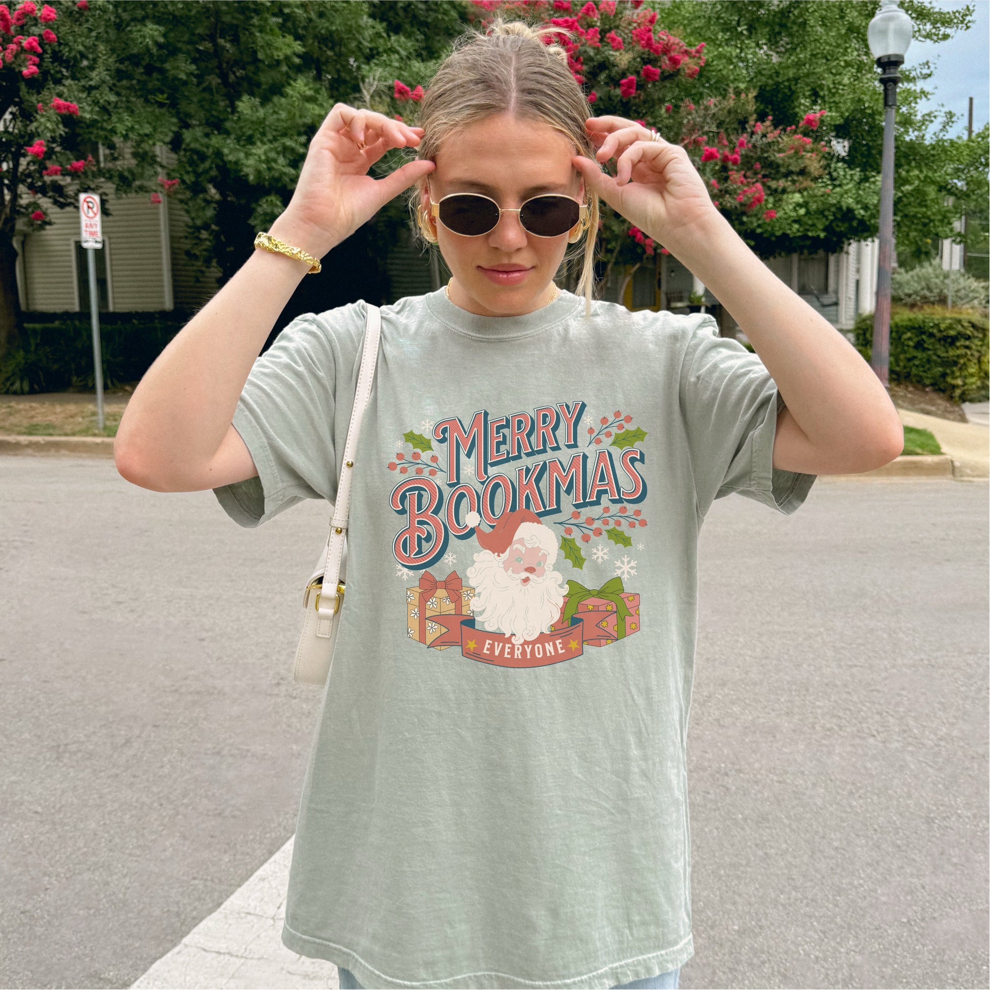 Woman wearing Merry Bookmas t-shirt with festive Santa and book design outdoors