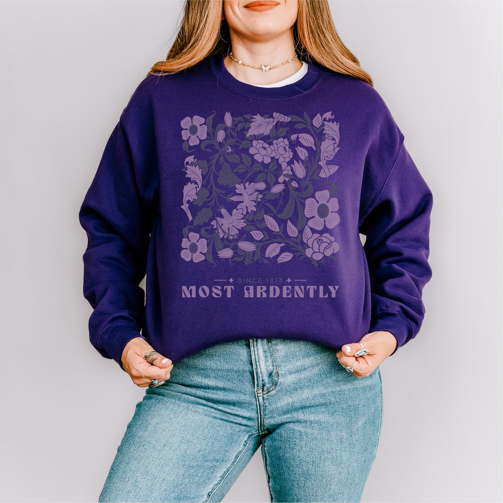 Purple floral sweatshirt with 'Most Ardently' text, worn with blue jeans