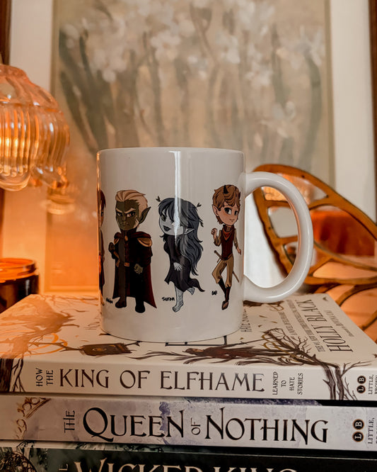 Mug with character designs on a stack of books titled 'The King of Elfhame' series.