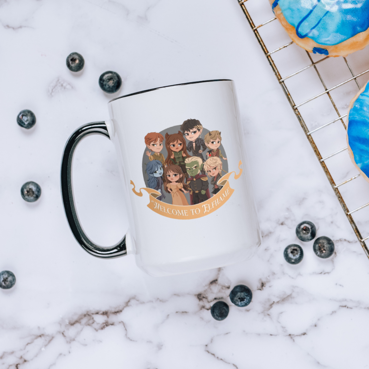 White mug with chibi fantasy characters and 'Welcome to Elfhame' text, on marble table