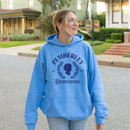 Woman in a blue Pemberley Derbyshire hoodie, standing outdoors on a residential street