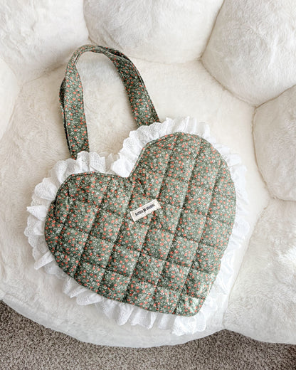 Heart-shaped quilted pillow with ruffles on a textured surface