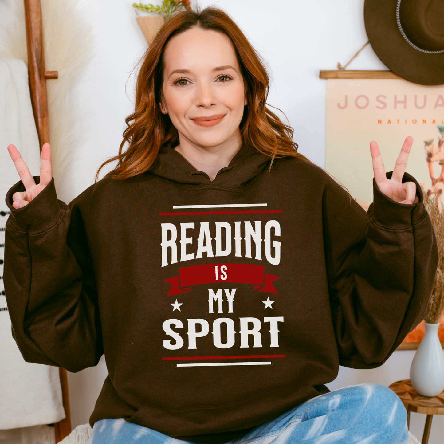 Woman wearing brown hoodie with 'Reading is my sport' text, bookish gift apparel