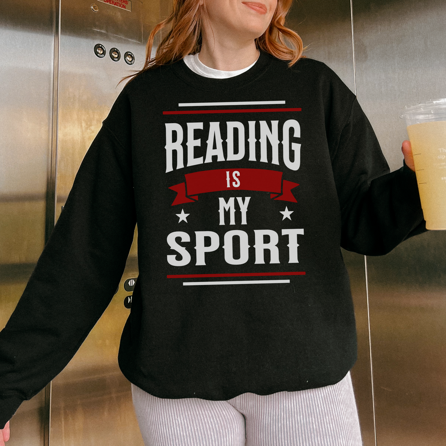 Woman wearing black crewneck sweater with 'Reading is my sport' book lover quote