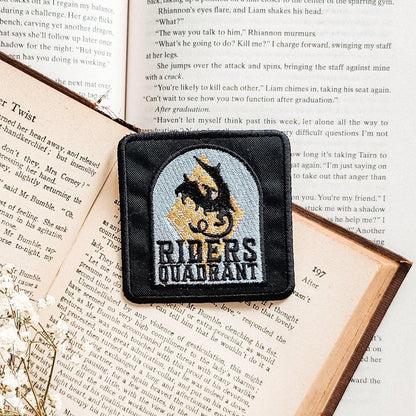 Riders Quadrant embroidered patch with dragon design on open book pages