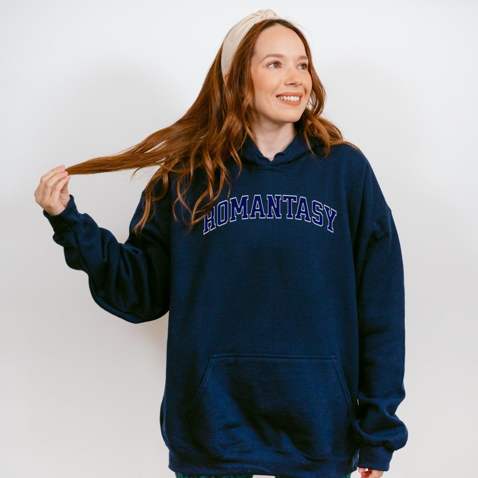 Woman wearing navy blue ROMANTASY hoodie, bookish apparel, front pocket, white background