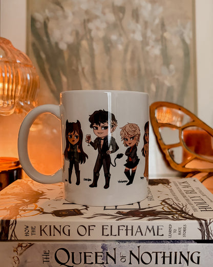 White mug with character illustrations on a stack of books titled 'The King of Elfhame', 'The Queen of Nothing', and 'Wicked King'.