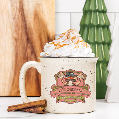 Speckled cream ceramic camp mug with whimsical mushroom illustration, topped with whipped cream.