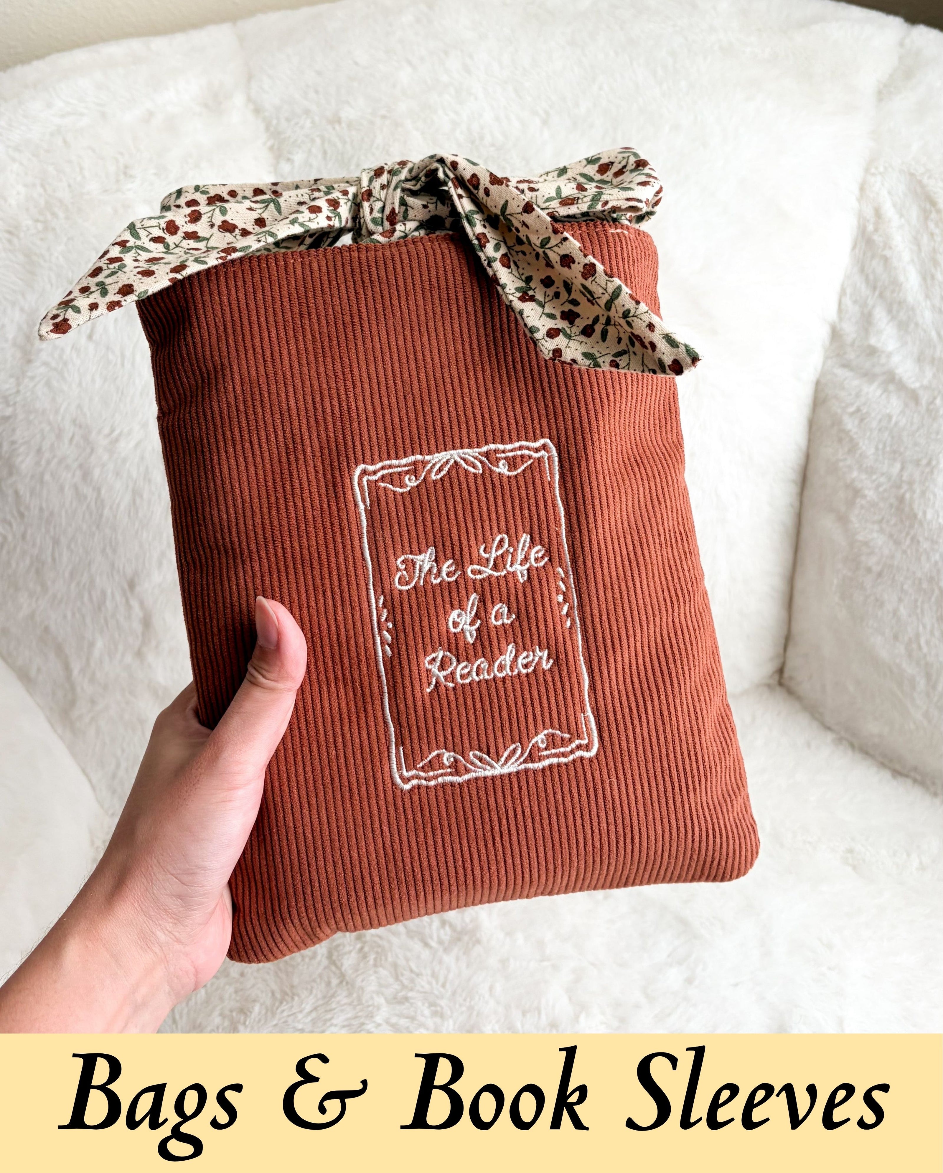 An elegant, texturized vintage corduroy book sleeve with an autumn floral tie closure, styled against a soft cream backdrop to highlight a cozy, wholesome storybook lifestyle.