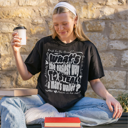 Woman wearing a black graphic bookish quote t-shirt, sitting outdoors with coffee and books