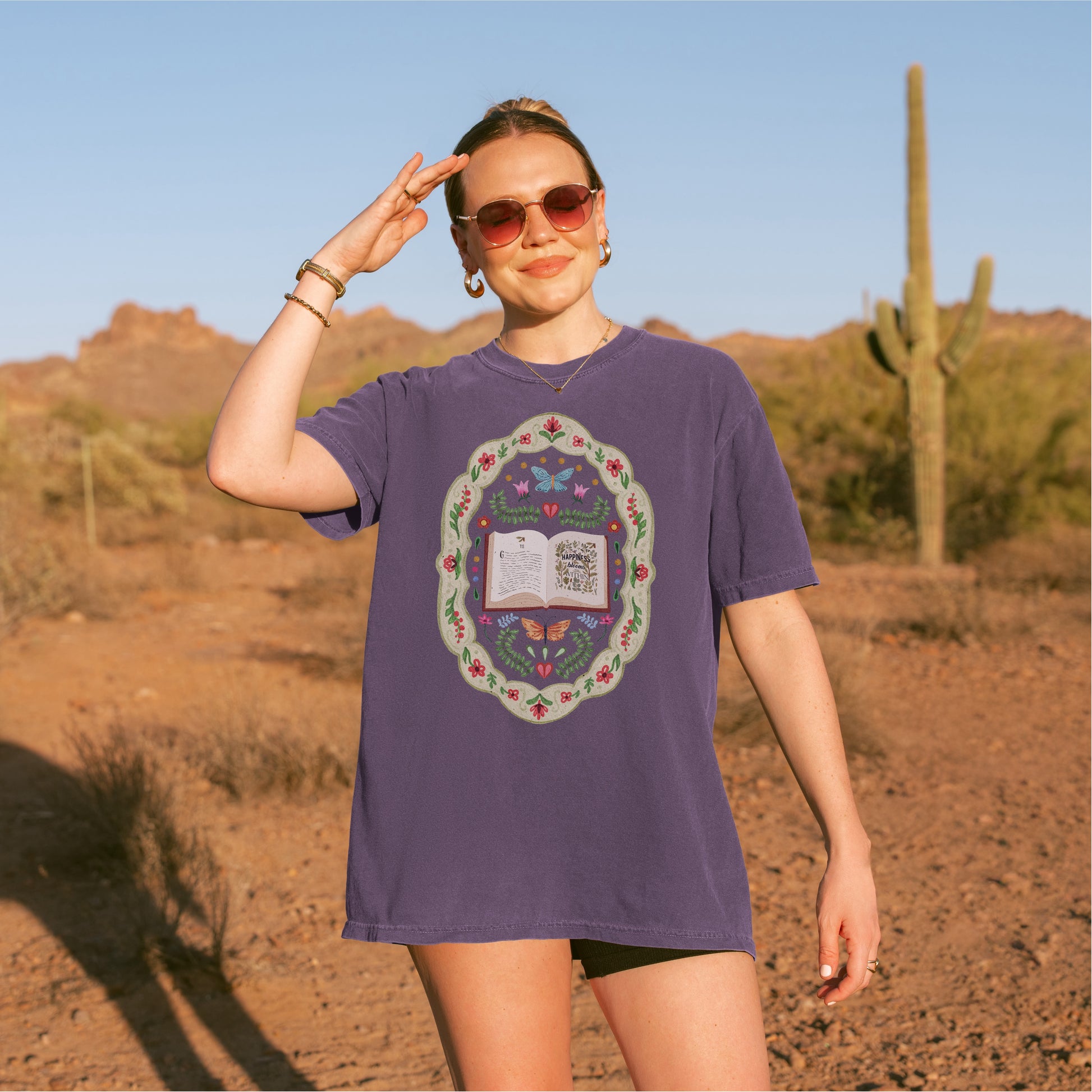 Woman wearing a purple whimsical folklore book t-shirt in a desert landscape
