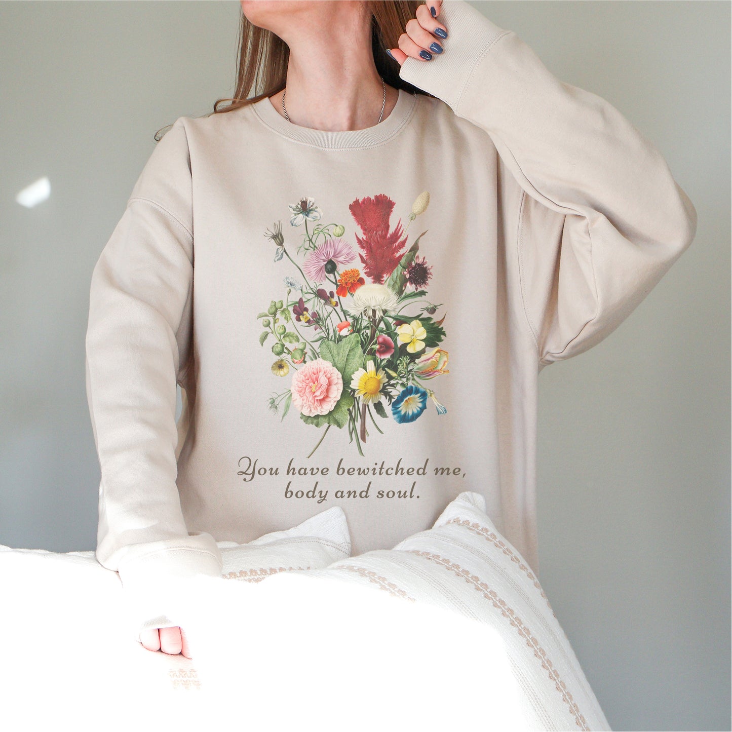 Woman wearing a beige sweatshirt with a colorful floral print and literary quote text.
